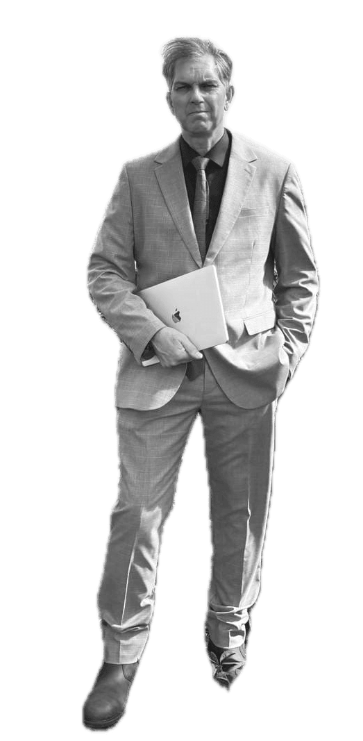Andrew Waterhouse, founder of Sacred Logic, standing holding a MacBook